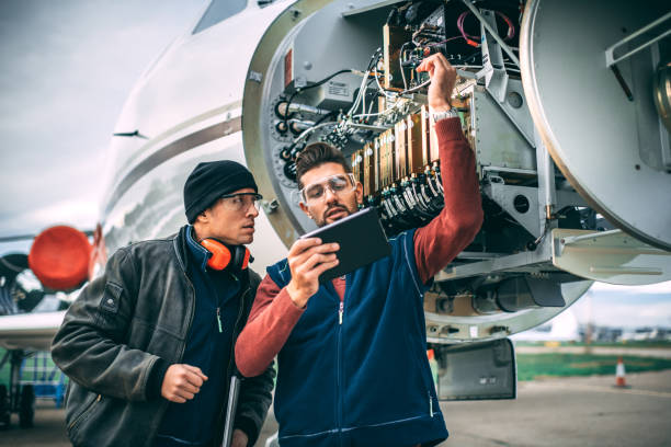 istock Two aircraft mechanics working on a radar array using a laptop and a digital tablet trying to diagnose a problem under the opened up nose cone of a private airplane parked on an airport field 1098231416