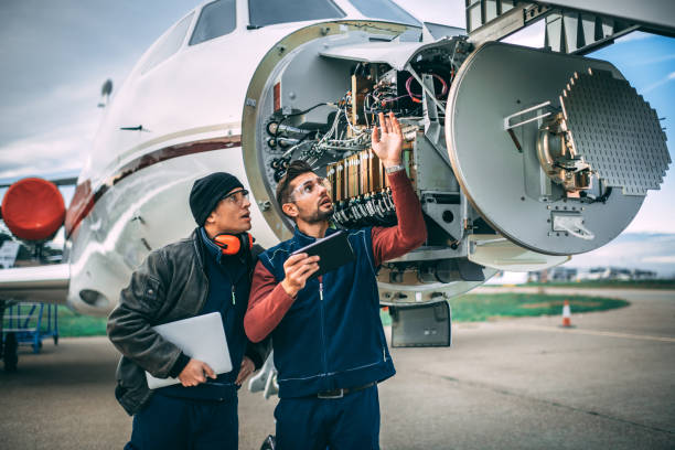 istock Two aircraft engineers fixing a problem on a sensor and radar array in the nose cone of a small private jet parked on an airport field 1098231424