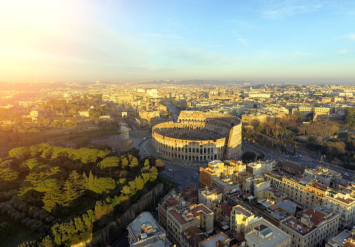 Flying over Colosseum, Rome, Italy. Aerial view of the Roman Coliseum on sunrise. Beautiful view of the famous Italian landmark, travel icon.