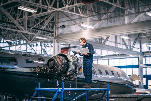 istock Aircraft mechanic standing on a raised work platform, looking at a display of a probe inspection camera, trying to diagnose a fault in a jet engine of a small private airplane in a maintenance hangar 1098232142