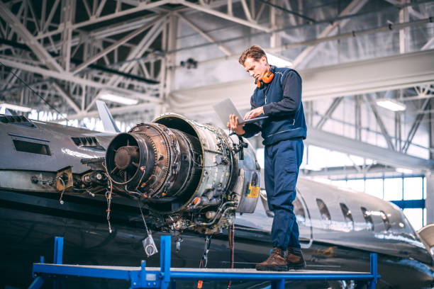 istock Aircraft mechanic holding a laptop and diagnosing a jet engine of a small airplane while standing on a raised platform in a hangar 1098232182