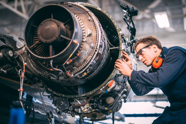 Aircraft mechanic in a hangar repairing and maintaining a small airplane's jet engine Aircraft engineer in the hangar repairing and maintaining an airplane jet engine. plane hand tool photos stock pictures, royalty-free photos & images
