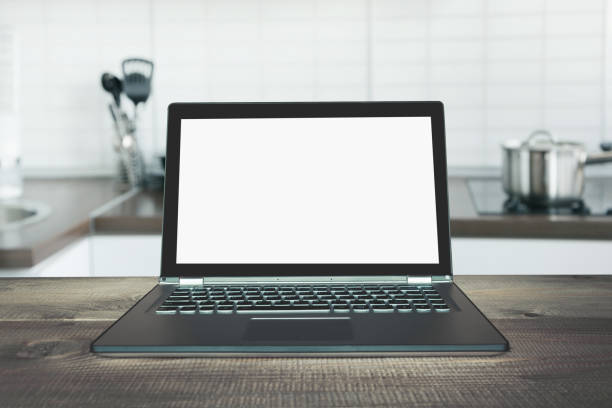 istock Laptop with empty blank screen on wooden tabletop with modern blur kitchen background. 1098235210
