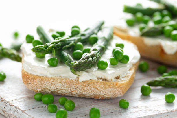istock Appetizer bruschetta, toast with Asparagus, Peas and creamy soft cheese. on white board. 1098246656