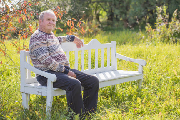 istock elderly man resting on white bench in autumn park 1098247910