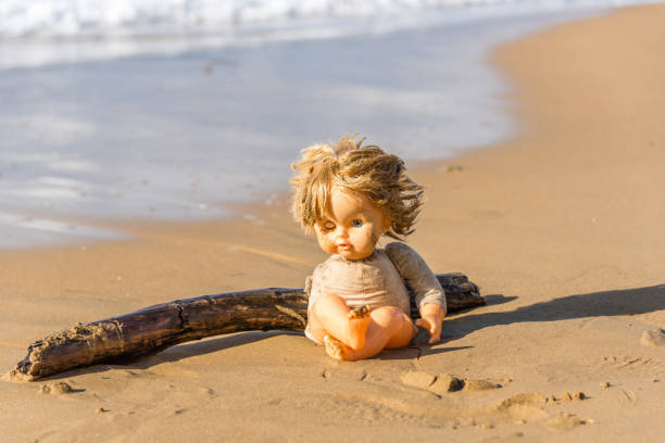 istock Cast Away Broken Doll Washed up on a Beach 1098247988
