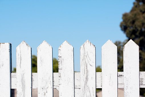 Wooden white fence, clear blue sky background in sunny weather. Image suitable for background purposes.