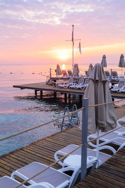 vue du ciel de l’aube romantique, mer et plateforme avec vide de chaises longues et parasols. - beach coral close up water photos et images de collection