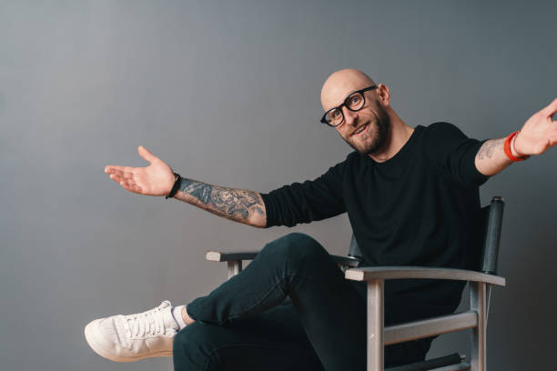 istock You are always welcome. Man with glasses gesturing and smiling while standing against grey background 1098257012