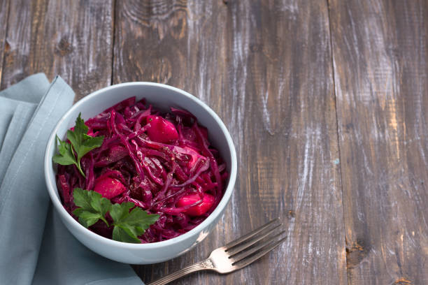 istock Stewed red cabbage with apples, spices and greens on a wooden background 1098259892