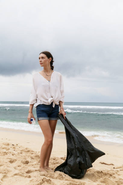 voluntário mulher coleta de lixo na praia. conceito de mares livre de lixo. plástico de uso único é um vício humano que está destruindo nosso planeta - mulher catando lixo - fotografias e filmes do acervo