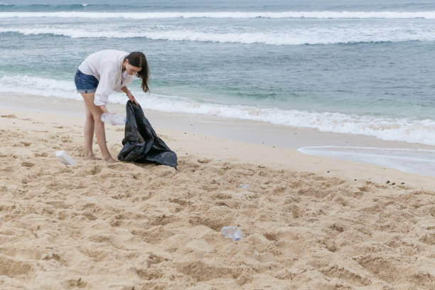 voluntário mulher coleta de lixo na praia. conceito de mares livre de lixo. plástico de uso único é um vício humano que está destruindo nosso planeta - mulher catando lixo - fotografias e filmes do acervo
