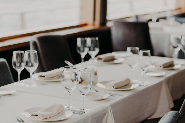 istock Catering and celebration concept. Festive served dinner table with glasses and cutlery on white tablewear in luxury banquet with no people. Table setting 1098267156