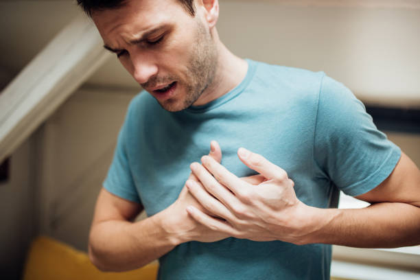 Ill man holding his chest Young man having strange chest pain chest pain stock pictures, royalty-free photos & images