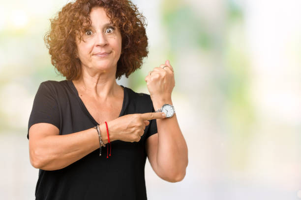 bella donna anziana ager centrale su sfondo isolato in fretta indicando il tempo di guardare il tempo, impazienza, sconvolto e arrabbiato per il ritardo della scadenza - checking the time women impatient wristwatch foto e immagini stock