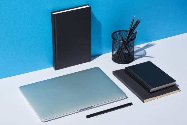 istock laptop, pencil holder and notebooks on white desk and blue background 1098293136