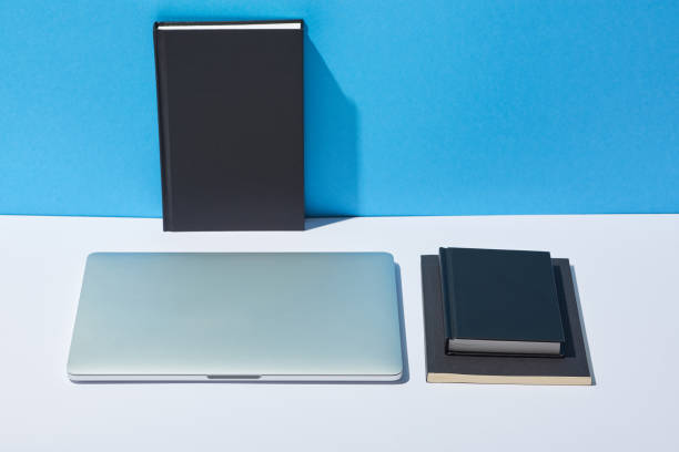 istock laptop and notebooks on white desk and blue background 1098293140