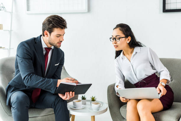 istock multiethnic businesspeople with notebook and laptop talking while sitting in waiting hall 1098298098