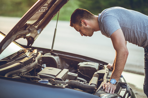 Young man repairing car on the side of the road