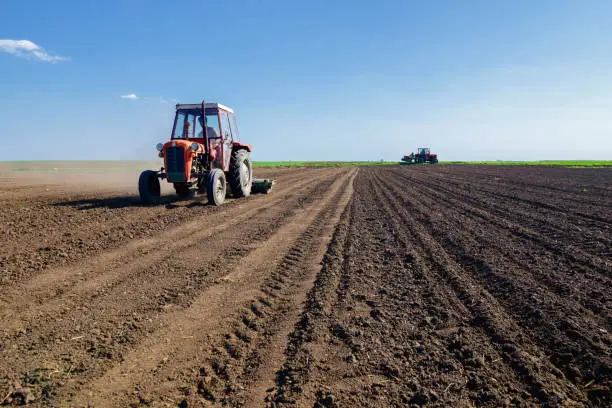 Tractors sowing on agricultural field on a beautiful sunny spring day.