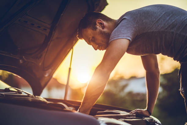 Looking under car hood Young man repairing car on the side of the road stranded stock pictures, royalty-free photos & images
