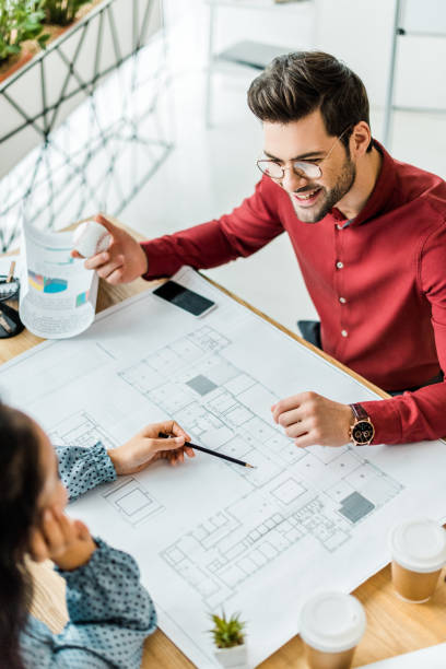 istock couple of architects sitting at table and working on blueprints in office 1098306082