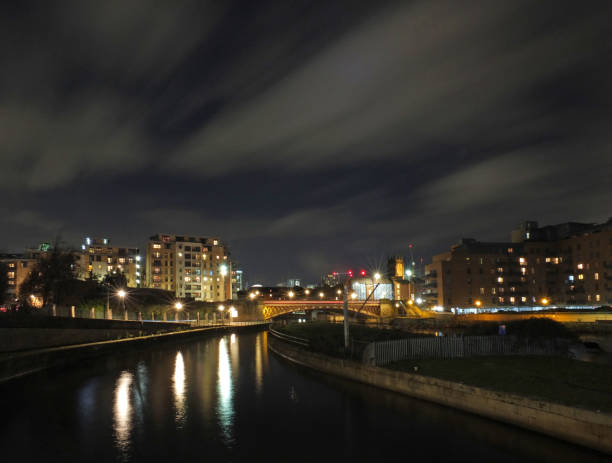 панорамный вид на город лидс ночью от реки эйр с мостом коронной точки и апартаментами, отраженными в воде и приходской церкви, освещенной с - uk river panoramic reflection стоковые фото и изображения