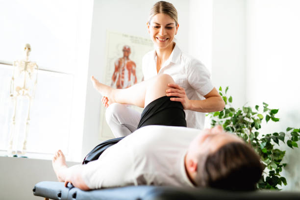 una trabajadora de rehabilitación moderno fisioterapia con cliente - physical therapy fotografías e imágenes de stock