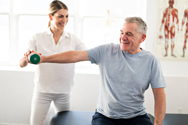 eine moderne rehabilitation physiotherapie arbeitskraft mit senior client - erholung stock-fotos und bilder