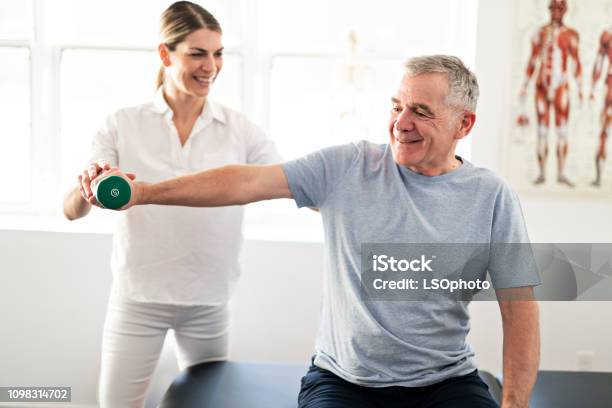 A Modern Rehabilitation Physiotherapy Worker With Senior Client Stock Photo - Download Image Now