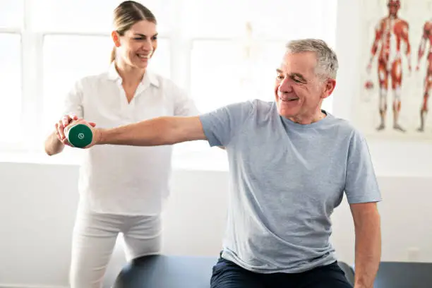 Modern rehabilitation physiotherapy worker with senior client