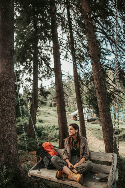 istock Young charming lady sitting on swing in forest 1098315178