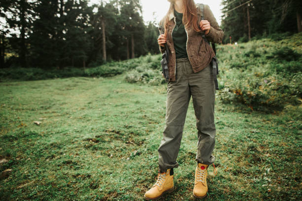 Stylish young lady standing on green meadow I am ready for adventures. Cropped portrait of active girl standing in beautiful forest. She is travelling alone with backpack timberland arizona stock pictures, royalty-free photos & images