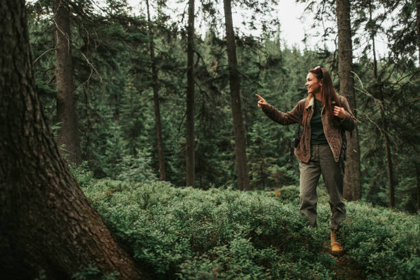 istock Cheerful girl pointing at something interesting while standing in forest 1098315346