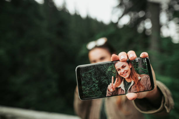istock Young lady holding smartphone with her selfie on display 1098315360