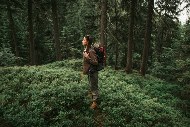 istock Serene girl with backpack standing in beautiful forest 1098315958