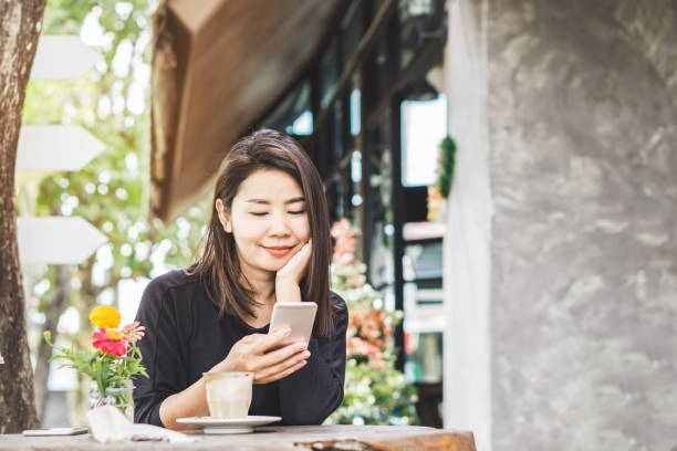 istock Asian woman using smart phone and drinking coffee in cafe 1098320574