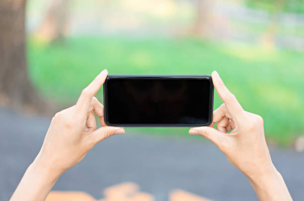 istock Hand holding smartphone with black screen on nature background. 1098341496