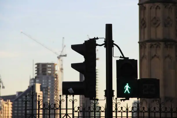 A traffic light showing green to pedestrians in front of a construction site.