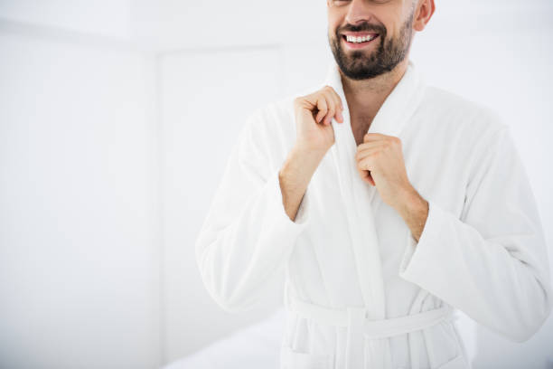 istock Cheerful bearded man touching his bathrobe and smiling 1098345600