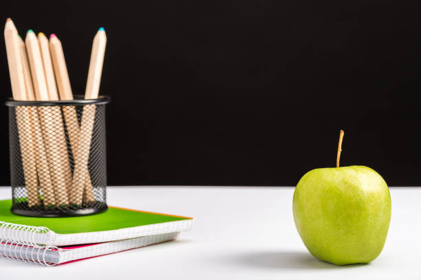 istock notebooks, pencils and apple isolated on black with copy space 1098347698