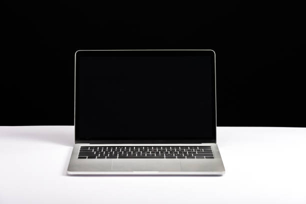 istock laptop with blank screen on white desk isolated on black 1098347722