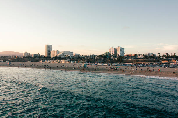 menschen am strand von santa monica bei sonnenuntergang - venice california santa monica pier sunset beach stock-fotos und bilder