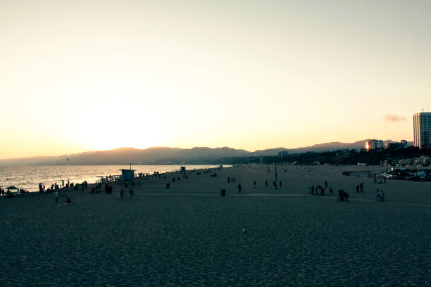 menschen am strand von santa monica bei sonnenuntergang - venice california santa monica pier sunset beach stock-fotos und bilder