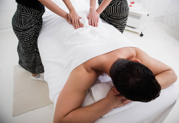 istock Man relaxing and two women giving him massage 1098349834