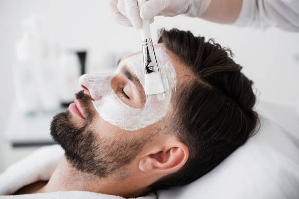 istock Close up of calm man smiling while getting white clay mask 1098349992
