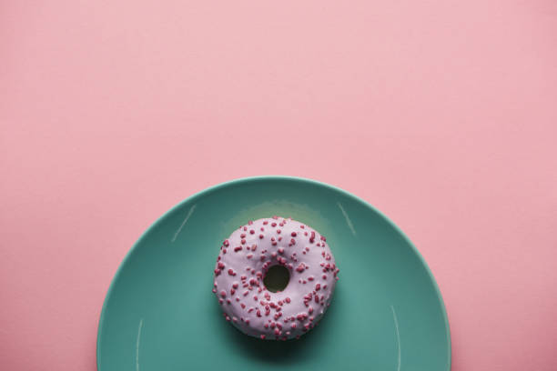 istock top view of glazed donut on blue plate isolated on pink 1098352382