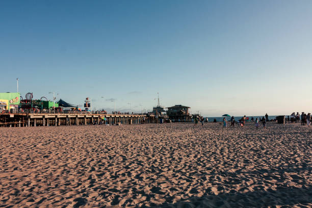 menschen am strand von santa monica bei sonnenuntergang - venice california santa monica pier sunset beach stock-fotos und bilder