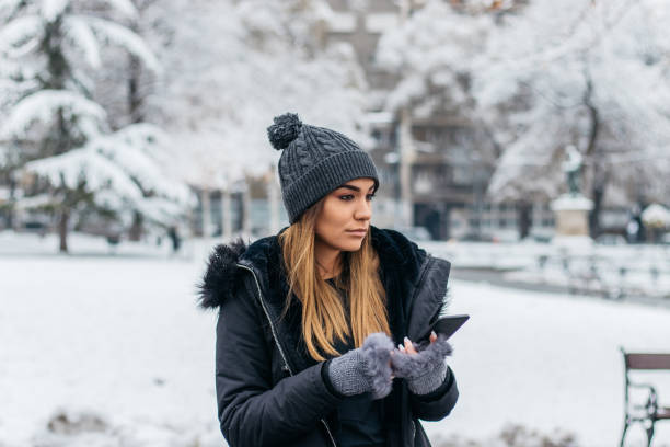 istock Charming woman texting in park covered with snow 1098353326