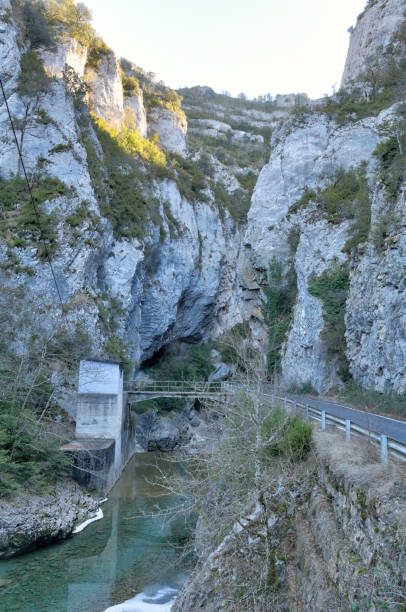 スペイン アラゴン州、フォス ・ ド ・ binies の農村地域における夕暮れ高灰色の岩渓谷と、固形の川峡谷に入る舗装道路 - conutryside ストックフォトと画像